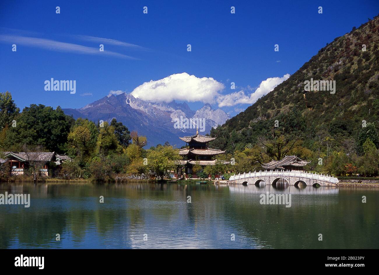 China: Jade Dragon Snow Mountain seen from Black Dragon Pool Park (H��il��ngt��n), Lijiang, Yunnan Province.  Black Dragon Pool, built in 1737 during the Qing period, is located slightly to the north of Lijiang's Old Town and offers one of China's most spectacular views.  Jade Dragon Snow Mountain is a small mountain range near Lijiang, in Yunnan province of southwestern China. Its highest peak is named Shanzidou (5,596 m or 18,360 ft). The far side of the mountain forms one side of Tiger Leaping Gorge (Hutiao Xia). Stock Photo