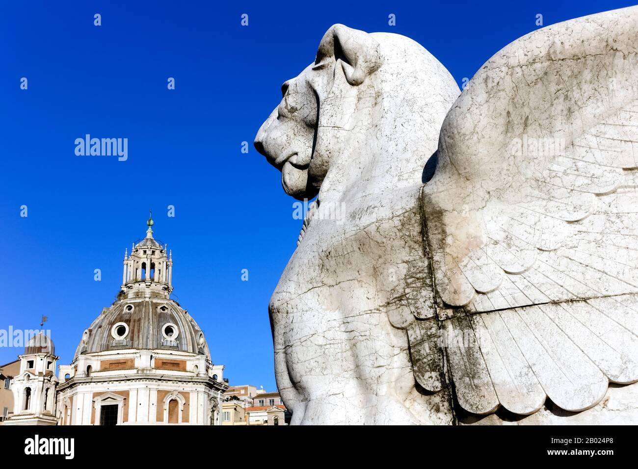 Winged lion sculpture, monument to Victor Emmanuel II. Altar of the fatherland. In the background dome of Church Holy Mary of Loreto. Rome. Close up Stock Photo