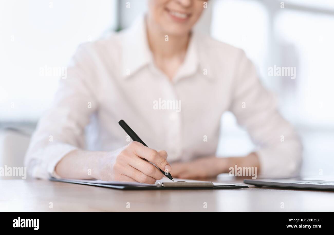 Lady Writing Short Account Of Career Sitting At Workplace, Cropped Stock Photo
