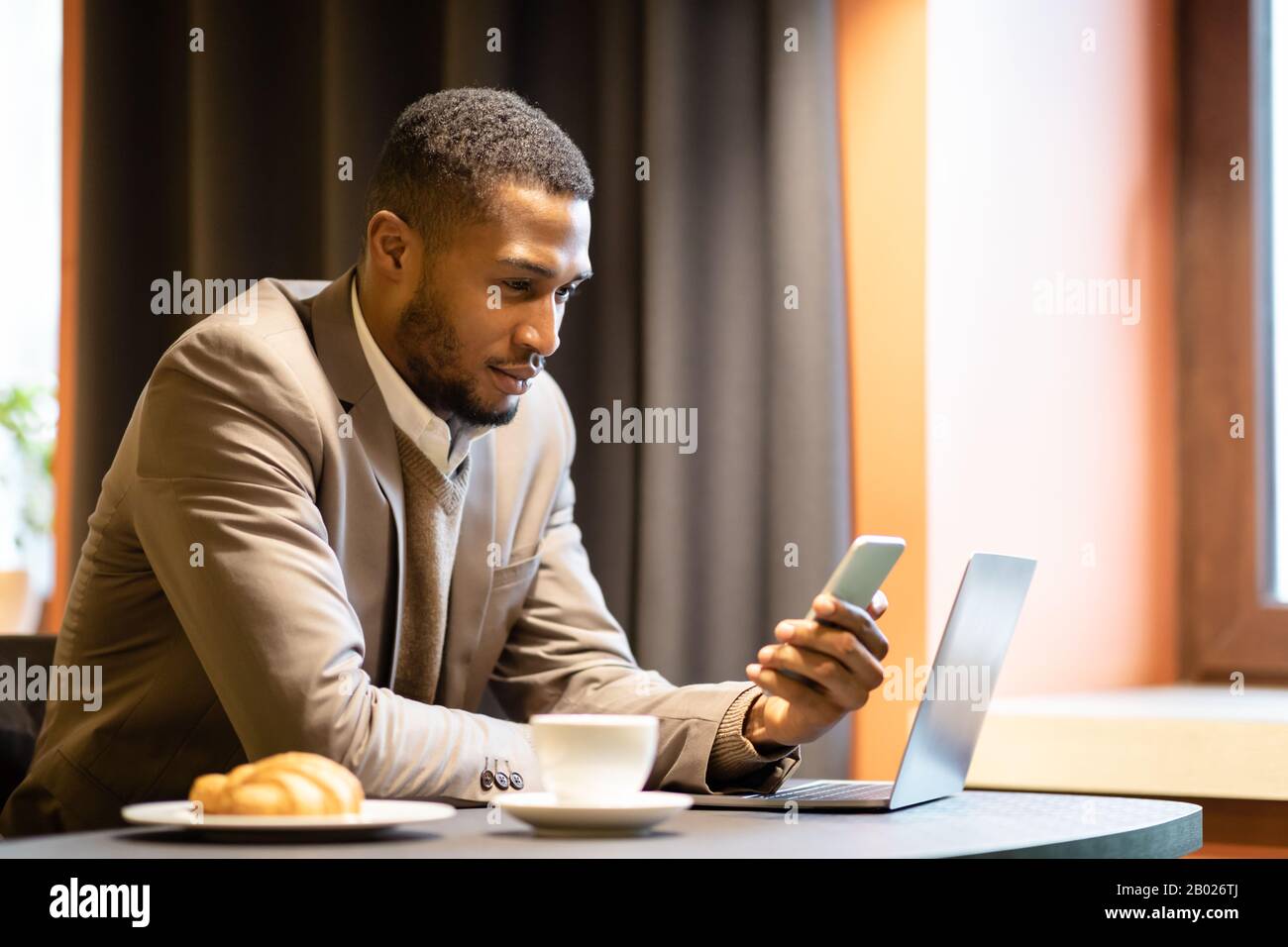 Portrait of afro guy using cellphone and computer Stock Photo