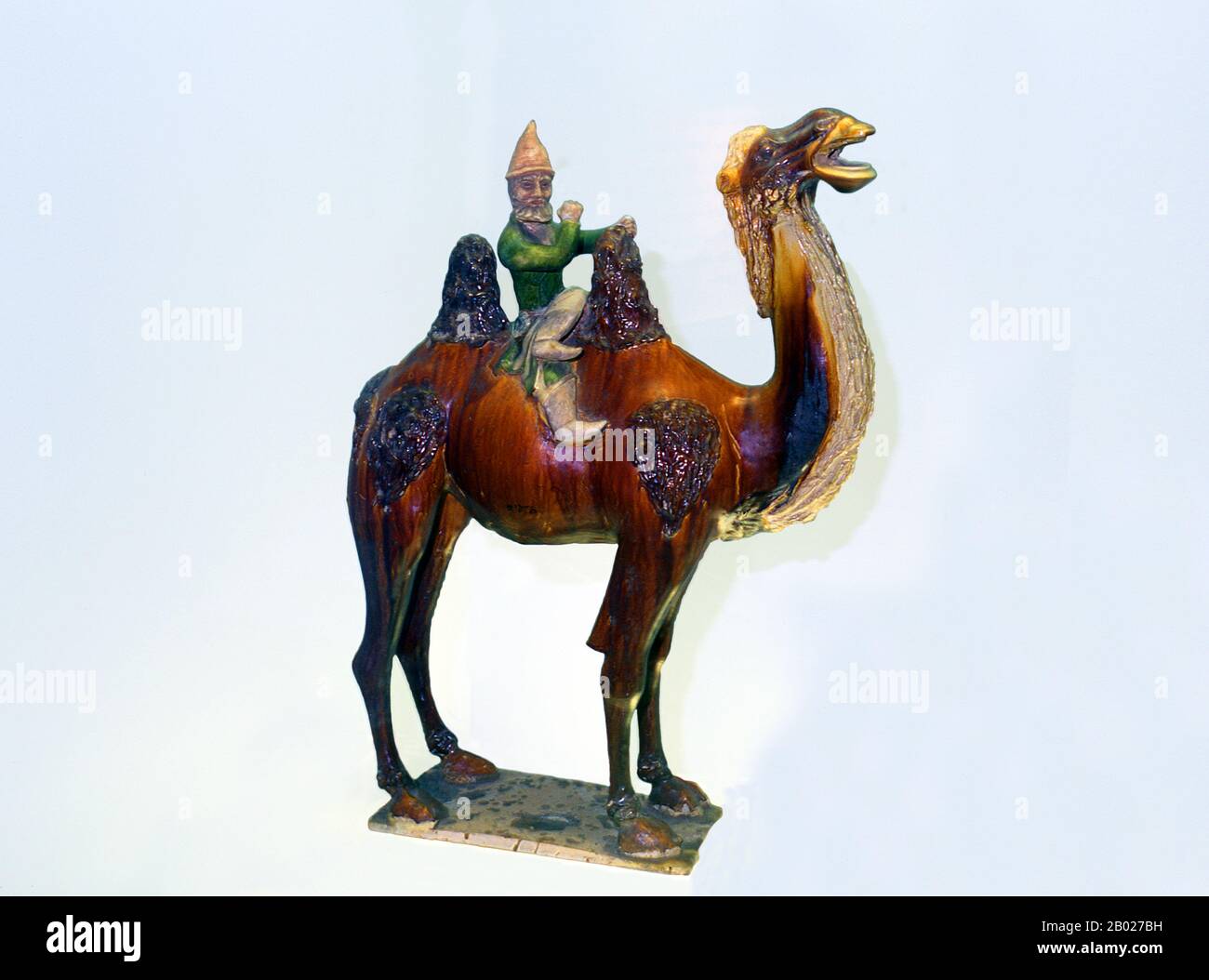 China: A Sogdian Silk Road trader on a Bactrian camel, Tang Dynasty (618-907) sancai ceramic, Shanghai Museum, Shanghai.  Sancai (literally 'three colours') is a type of ceramics using three intermingled colours for decoration.  The Tang Dynasty was an imperial dynasty of China preceded by the Sui Dynasty and followed by the Five Dynasties and Ten Kingdoms Period. It was founded by the Li family, who seized power during the decline and collapse of the Sui Empire. The dynasty was interrupted briefly by the Second Zhou Dynasty (690-705) when Empress Wu Zetian seized the throne. Stock Photo
