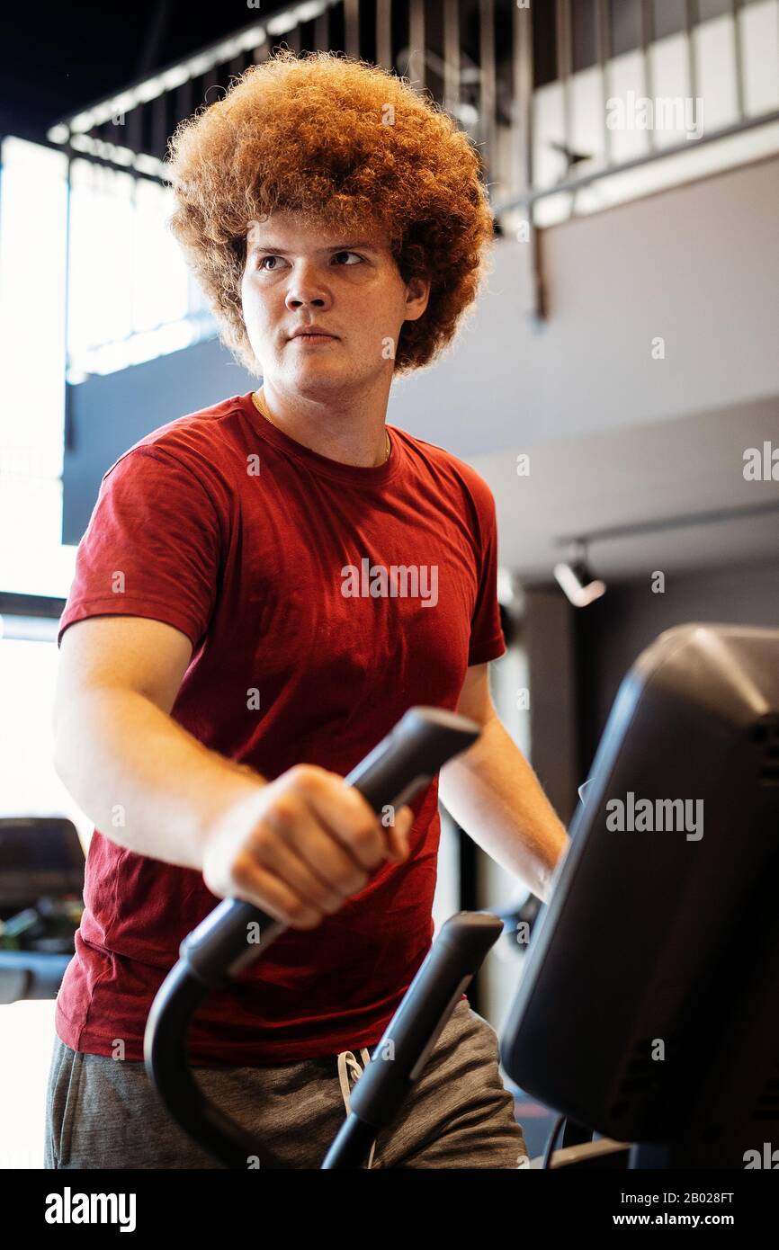 Overweight young man exercising in gym to achieve goals Stock Photo