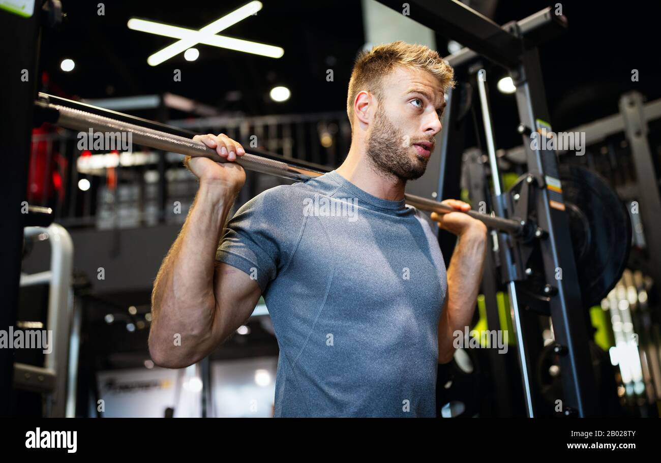 Man with weight training equipment exercising in sport gym club Stock Photo Alamy