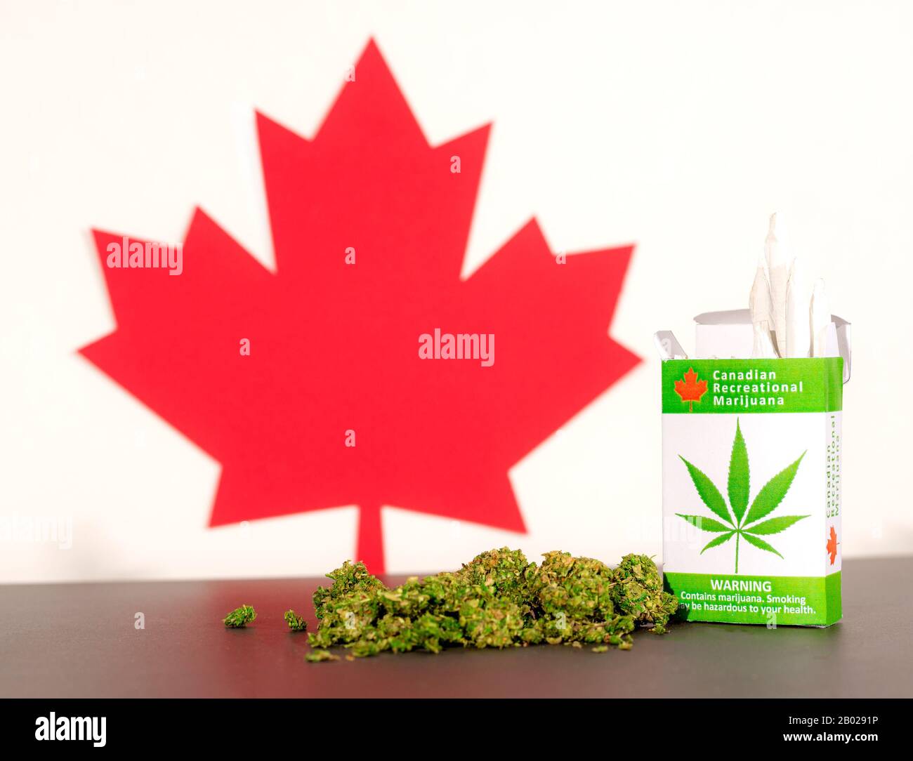 Cannabis in Canada. A package of cannabis cigarettes on a table, with a Canadian maple leaf behind. Marijuana buds on the table. Stock Photo