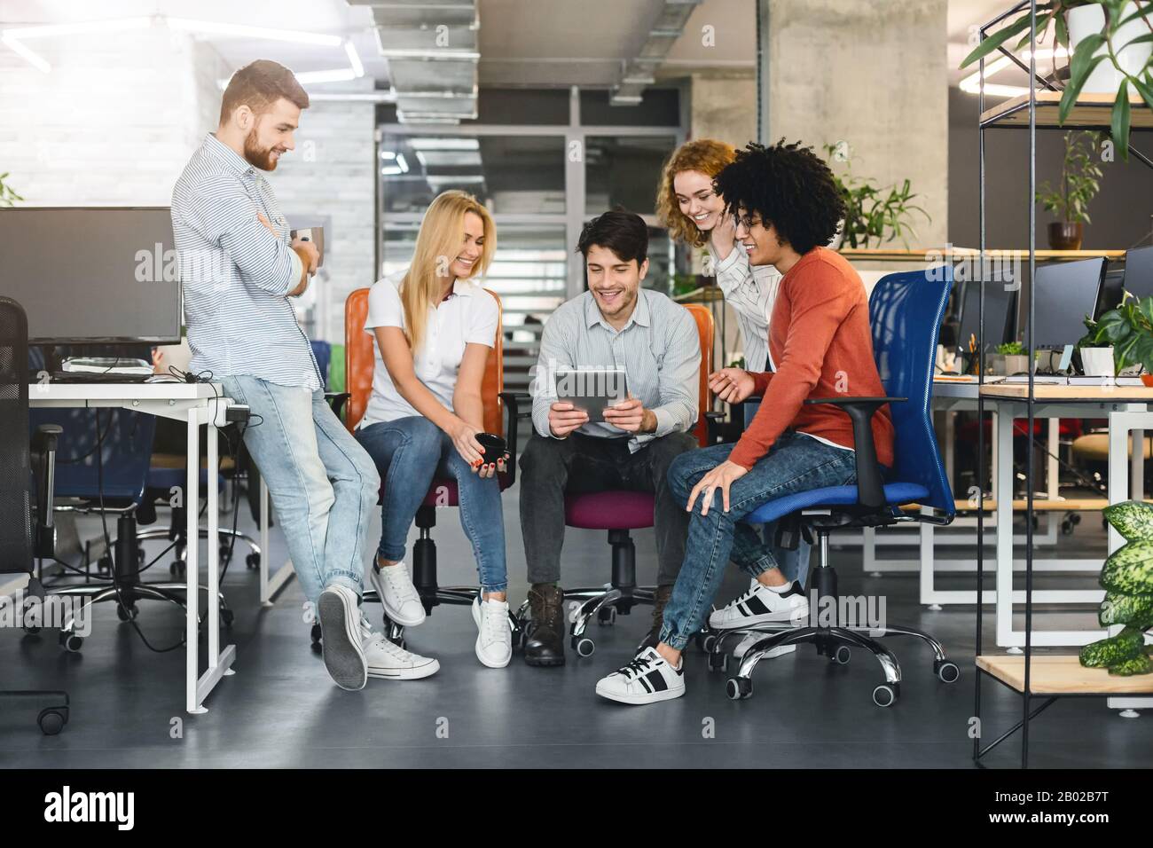 Young creative team discussing new project, using digital tablet Stock Photo