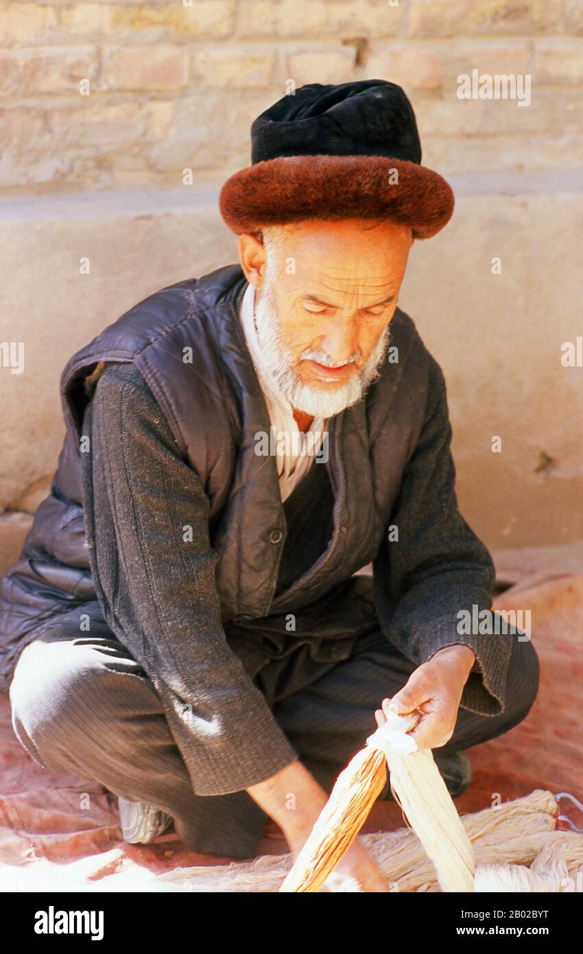 China: A Uighur man sorting raw silk threads, Atlas Silk Workshop (Atlas Karakhana) in Jiya Village, about 13km northeast of Khotan, Xinjiang Province.  During the first half of the 1st century CE, silk worm technology is thought to have reached the Han-Chinese dominated oasis of Khotan in the Tarim Basin - an oasis that is still a centre of silk production today. A Chinese princess given in marriage to a Khotan prince is said to have carried the eggs of silkworms to her new husband concealed in her hair. Stock Photo