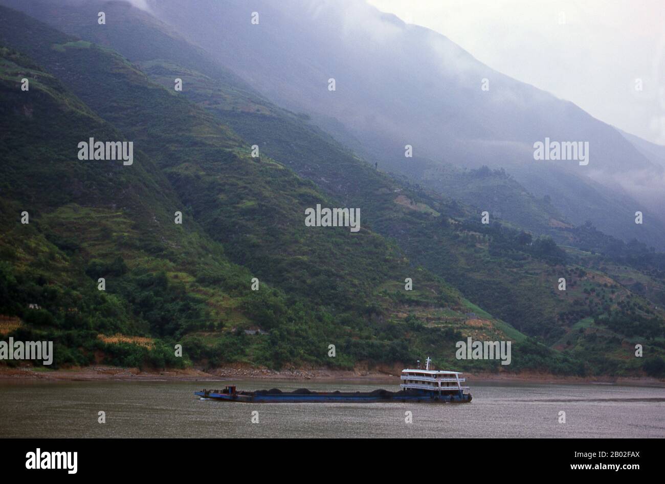China: Coal boat, early morning in the Qutang Gorge, smallest of the Three Gorges, Yangtze (Yangzi) River.  The Three Gorges or Yangtze Gorges span from the western - upriver cities of Fengjie and Yichang in Chongqing Municipality eastward - downstream to Hubei province.  The Yangtze River (Chang Jiang) - Three Gorges region has a total length of approximately 200 kilometres (120 mi). The Three Gorges occupy approximately 120 kilometres (75 mi) within this region.  The Chang Jiang (Yangzi River) is the longest river in China and third longest in the world. Stock Photo