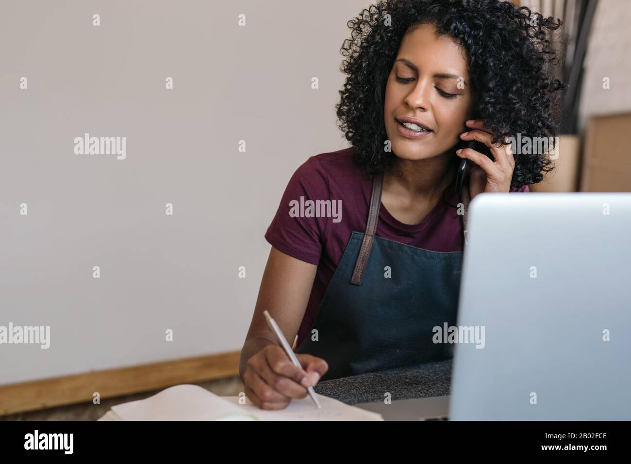 Entrepreneur talking on the phone while working in her studio Stock Photo