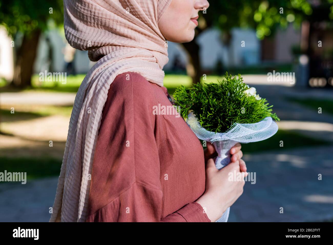 Woman in hijab graceful holding bouquet of green flowers Stock Photo