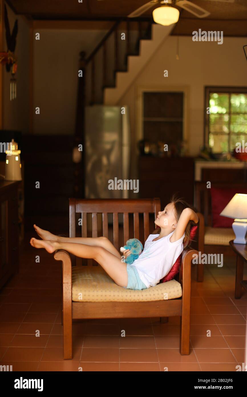 Little girl sitting in chair in living room Stock Photo - Alamy