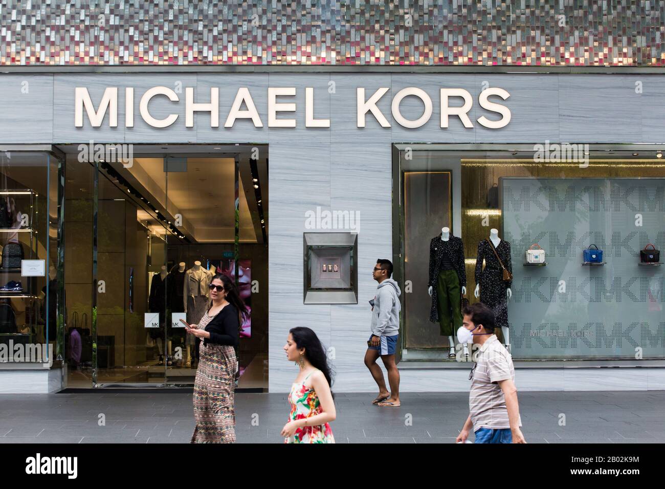 Indian tourists walking pass a high end luxury brand shop along Orchard Road, Singapore. Stock Photo