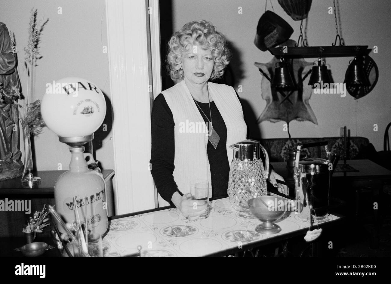 Evelyn Künneke, deutsche Sängerin, Tänzerin und Schauspielerin, in ihrer Hausbar in Hamburg, Deutschland um 1984. German singer, dancer and actress Evelyn Kuenneke behind the counter of her private bar at Hamburg, Germany around 1984. Stock Photo