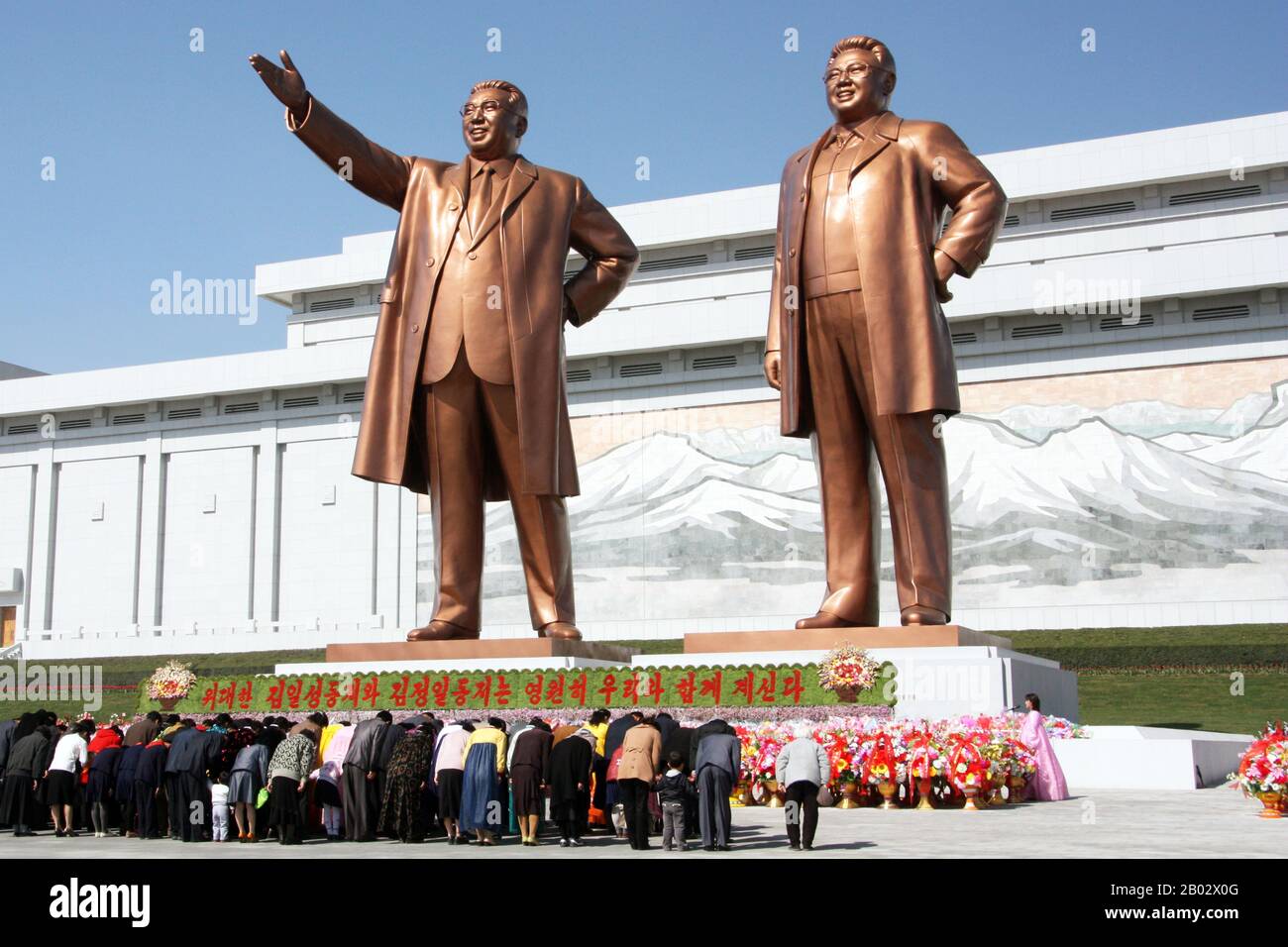 The Grand Monument on Mansu Hill (Mansudae) is a complex of monuments in Pyongyang, North Korea.  The central part of the monument are two 22 metre high bronze statues of North Korean leaders Kim Il-sung and Kim Jong-il. Behind the statues is a wall of the Korean Revolution Museum building, displaying a mosaic mural showing a scene from Mount Paektu, considered to be the sacred mountain of revolution.  The monument was constructed in April 1972, then displaying only Kim Il-sung. Following the death of Kim Jong-il, a similar statue of him was erected on the left side of Kim Il-sung. Stock Photo