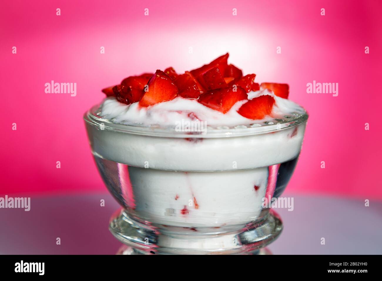 Ready-to-eat strawberry yogurt in a crystal glass on a pink background Stock Photo