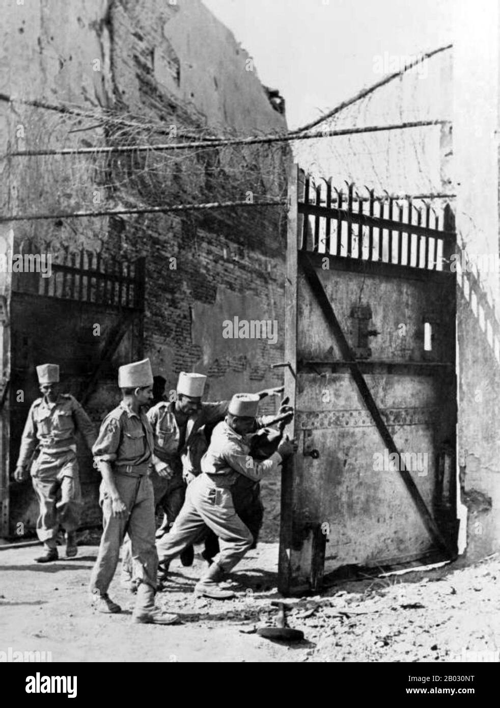 Indian soldiers of the Madras Engineer Group (MEG) try to pull the gates shut at Mandalay Palace (Fort Dufferin) following the Japanese retreat after the Allied British and Indian victory of the Battle of Meiktila and Mandalay during the Burma Campaign. Mandalay, Mandalay Region, Burma (Myanmar). March 1945. Stock Photo