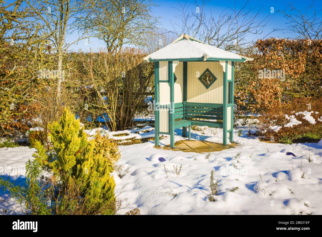 Winter snow fall transforms the pleasure garden, concealing many small plants and adding light to seasonal greyness. An arbour is still reachable and useful on sunny days Stock Photo
