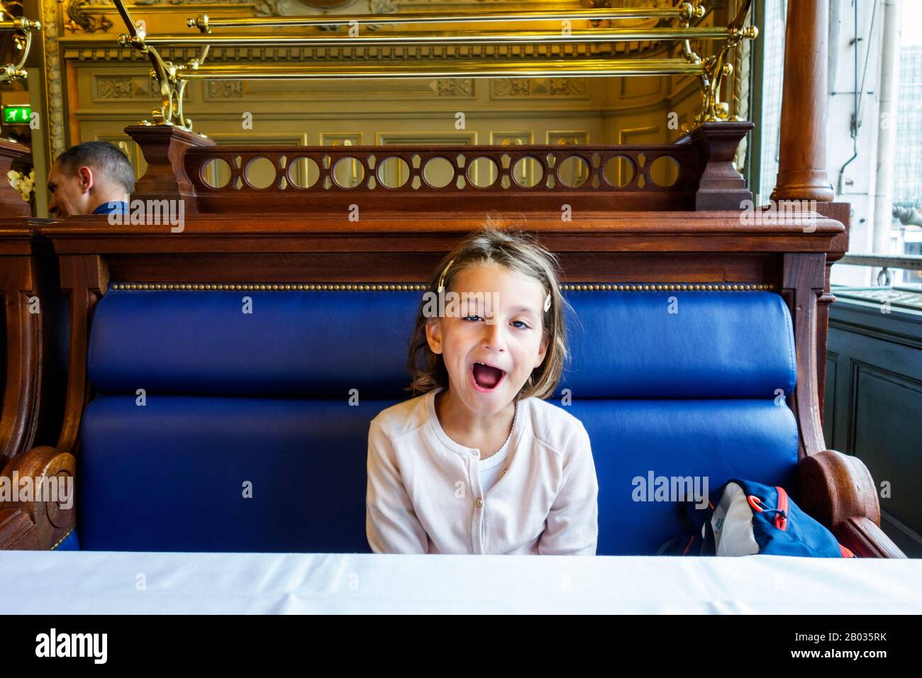 Young girl yawning in le Train Bleu, french restaurant located in the Gare de Lyon railway station in Paris. The restaurant was created in 1900. Stock Photo