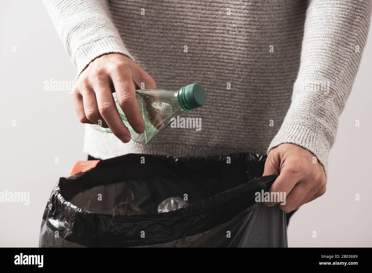 closeup of a young caucasian man about to throw an empty plastic bottle to the trash bin Stock Photo