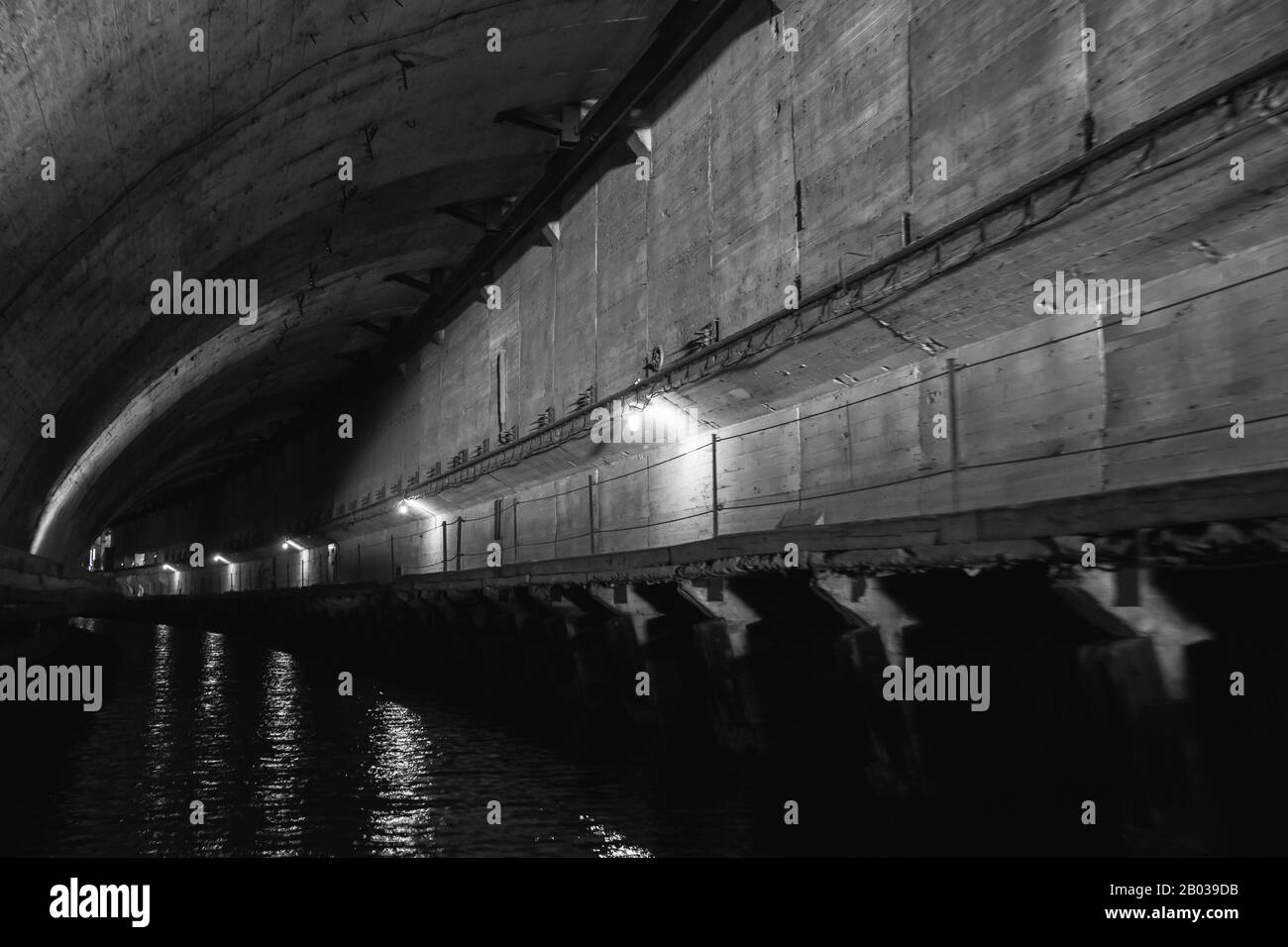 Dark concrete tunnel perspective, part of abandoned underground submarine base from USSR period. Balaklava, Crimea. Black and white Stock Photo
