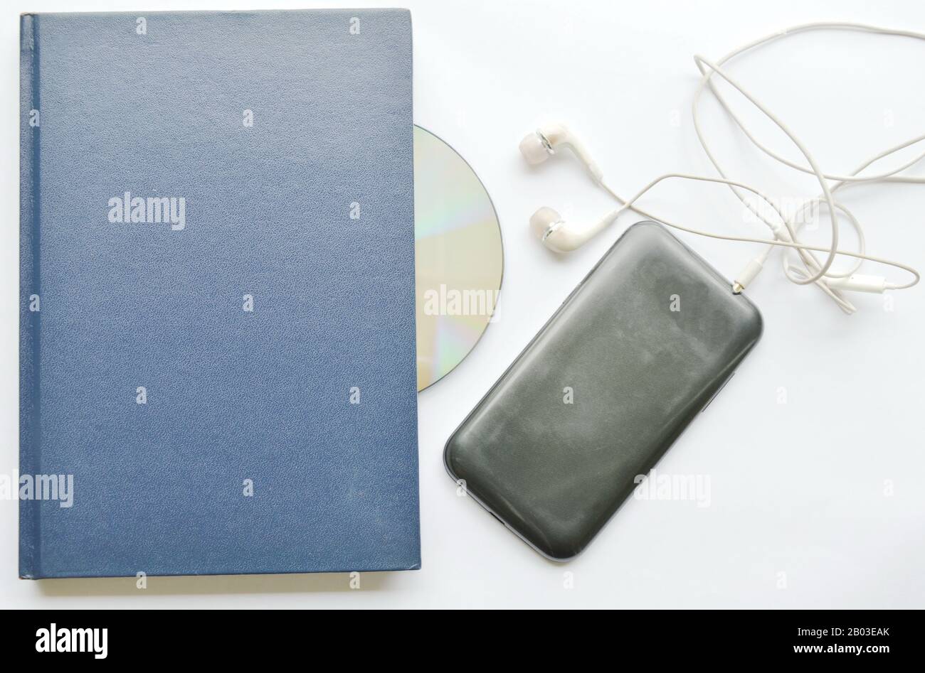 book and earphones connect in smartphone on white background Stock Photo