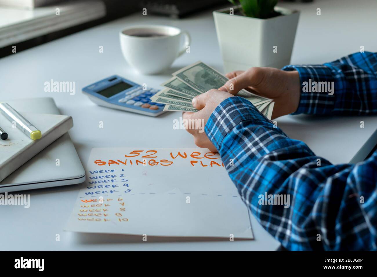 a 52 week saving plan, person count money and calculate the future Stock Photo Alamy