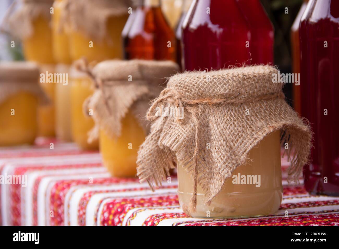 Various types of honey and honey drinks are on a table covered with a bright tablecloth with a rustic look Stock Photo