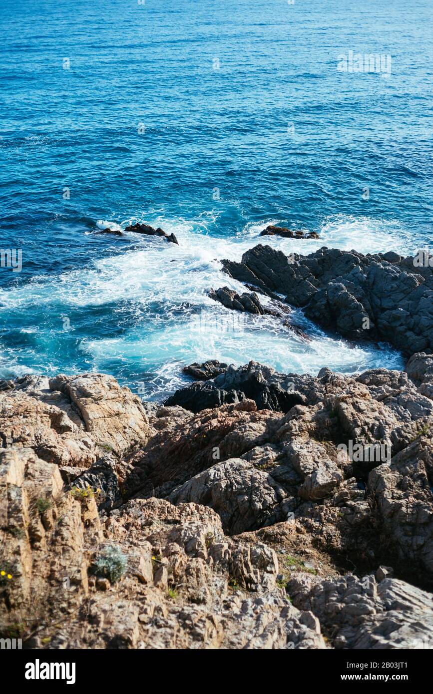 Aerial view of ocean waves and brown rocks in the coastline Stock Photo