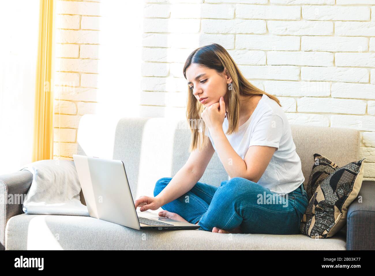 young attractive woman at home tiredly seeking for a job or rent in internet Stock Photo