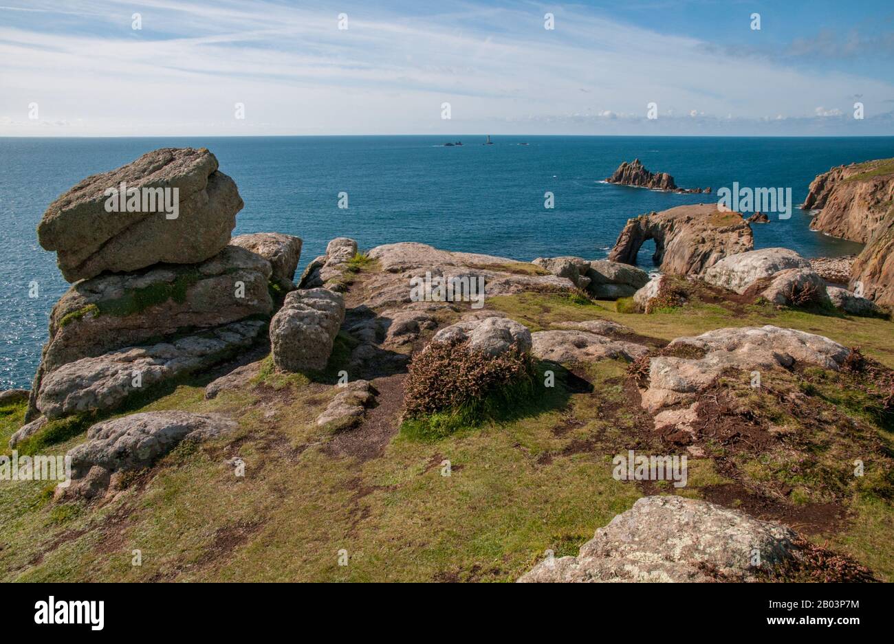 Views over the Celtic Sea from Land's End, Cornwall, across the dramatic landscape, skerries and Longships Lighthouse in the distance. Stock Photo