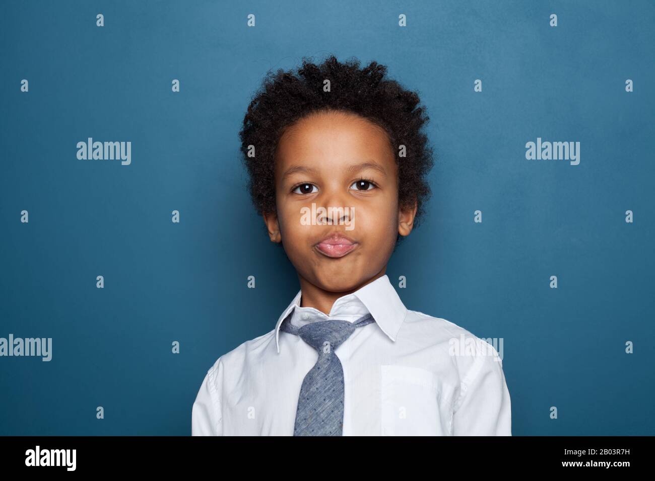 Portrait of little funny black kid boy on blue background Stock Photo