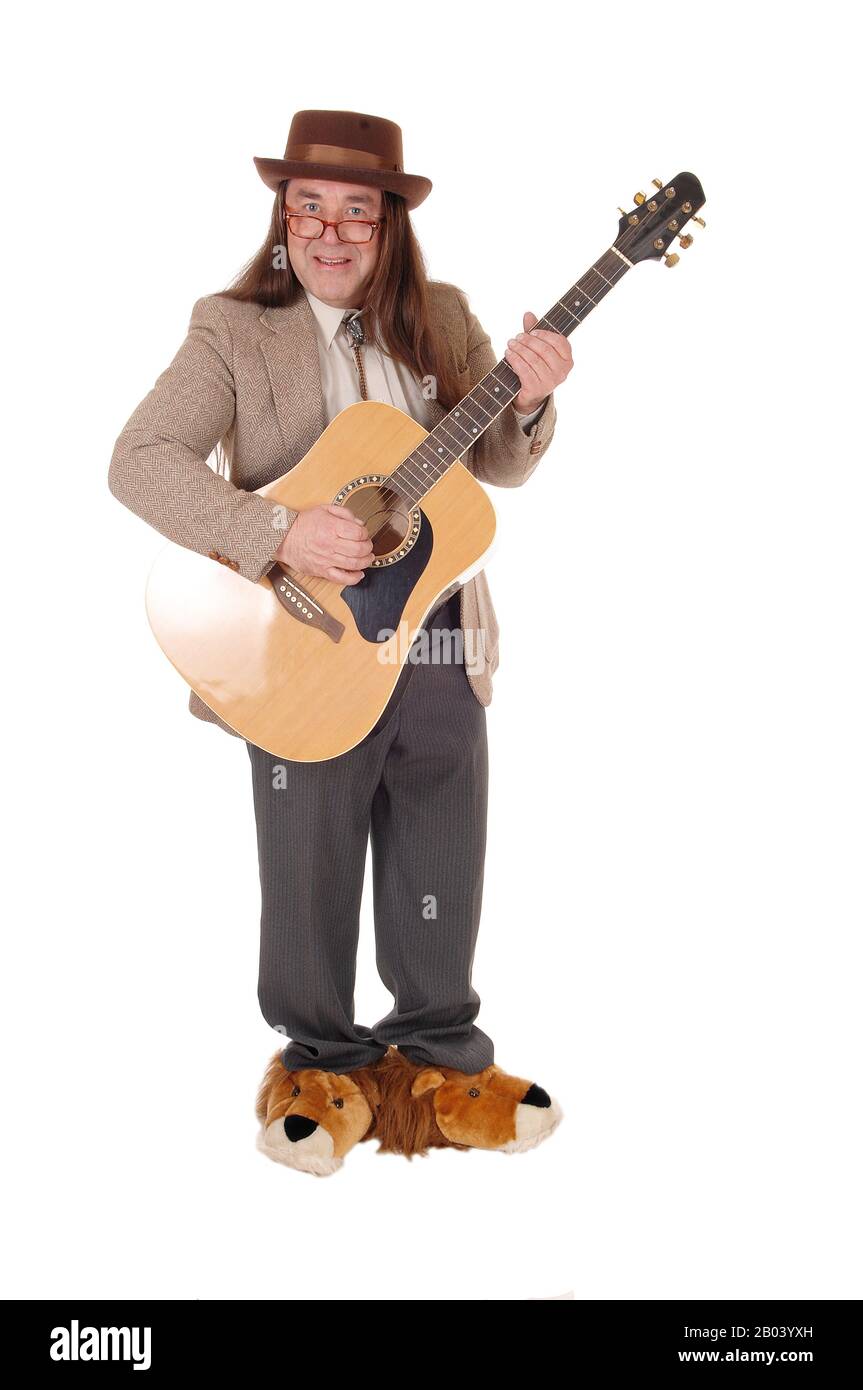 A middle age indigenous man in fancy shoes standing and playing his guitar in a jacket and hat, isolated for white background Stock Photo