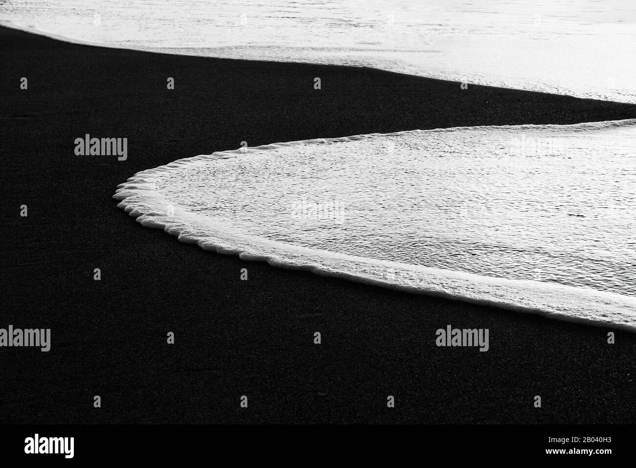 curvy wave in the sand shore of beach in black and white Stock Photo