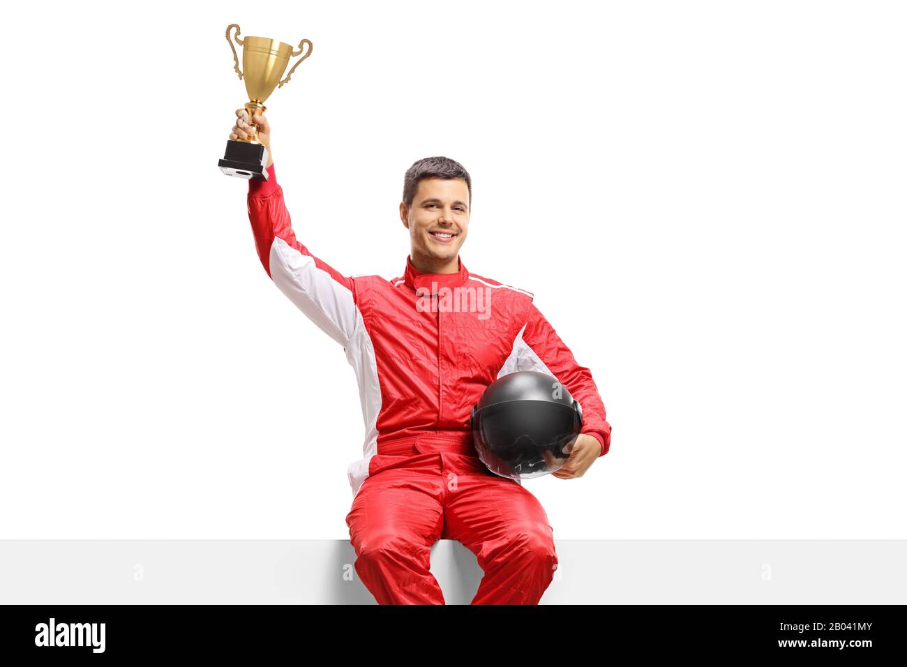 Racer in a suit holding a gold trophy cup and sitting on a panel isolated on white background Stock Photo