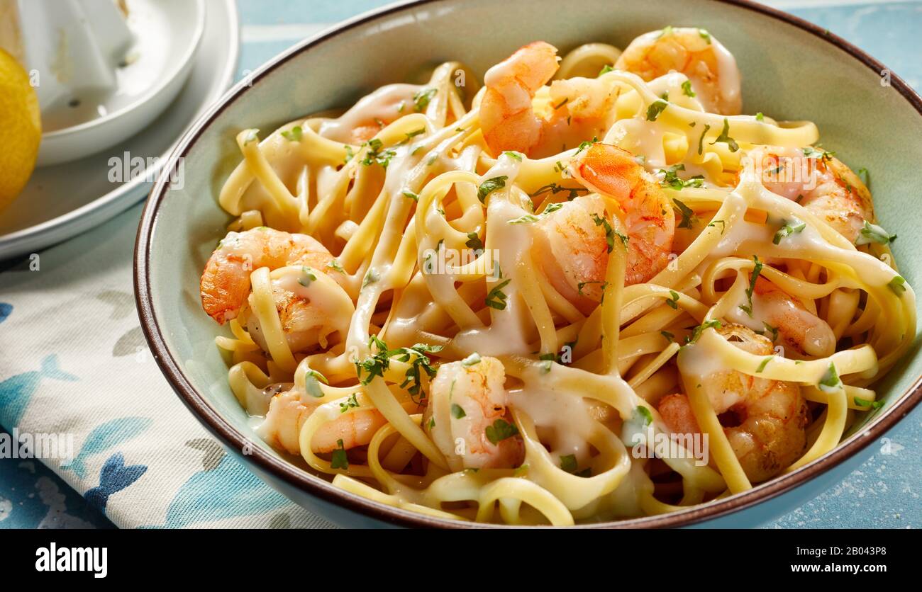 Bowl of fresh scampi with Italian noodles sprinkled with fresh green herbs and melted parmesan cheese in close up for a gourmet Italian or Mediterrane Stock Photo