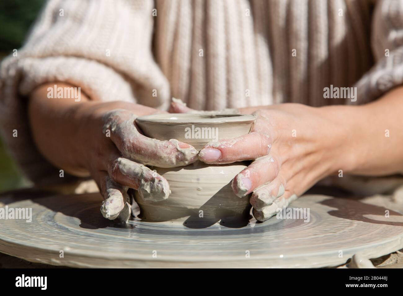 Womans hands working of ceramics with clay on a potter wheel Stock Photo