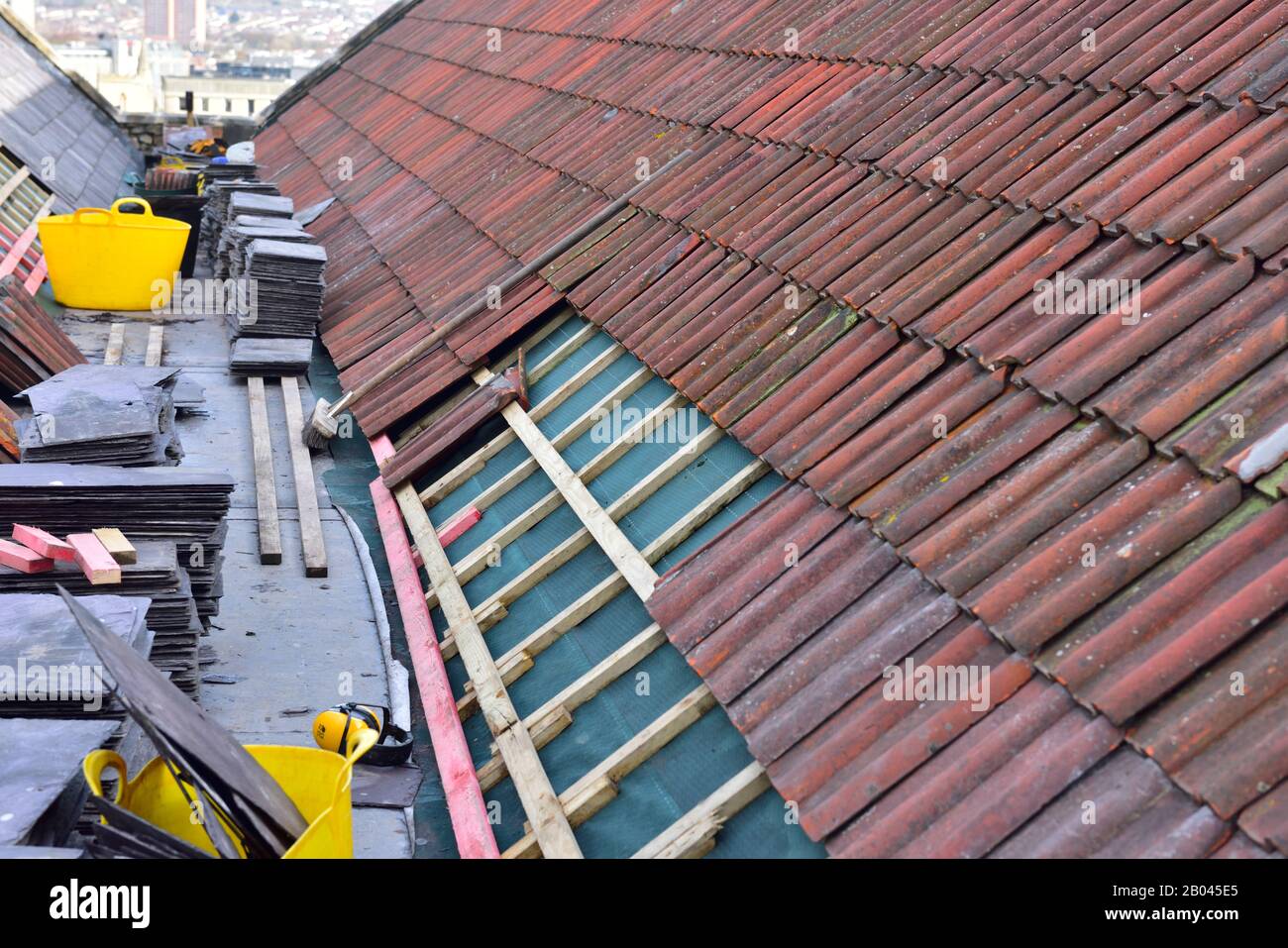 Tile and slate roof being rebuilt being rebuilt during building refurbishment, England, UK Stock Photo