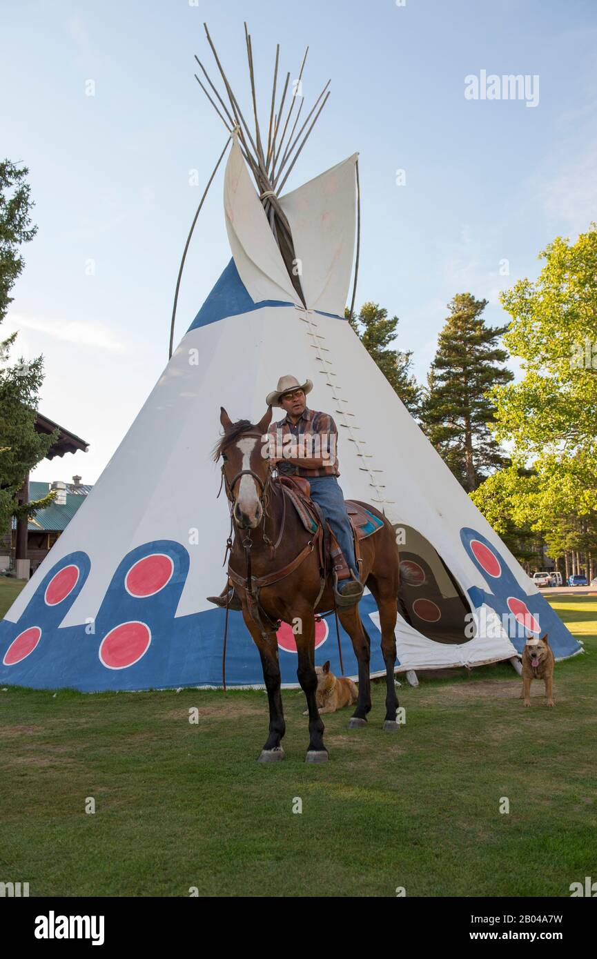 Chief Little Dog, a Blackfoot Native American, on his horse in front of a tipi at Glacier Park Lodge which is located just outside the boundaries of G Stock Photo