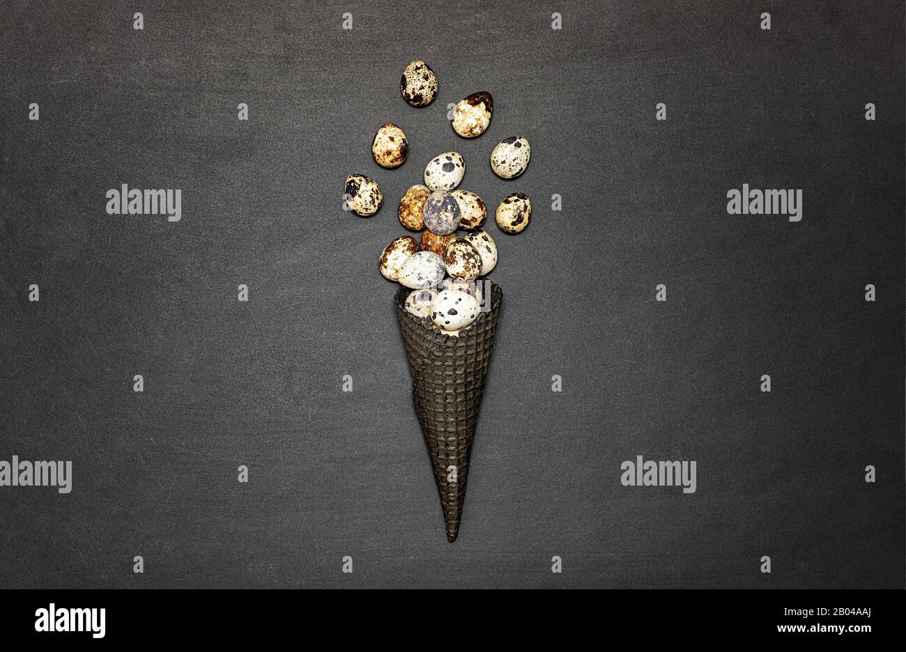 Dark waffle cone with easter eggs on a black background. Space for text. View from above. Flat lay. Stock Photo