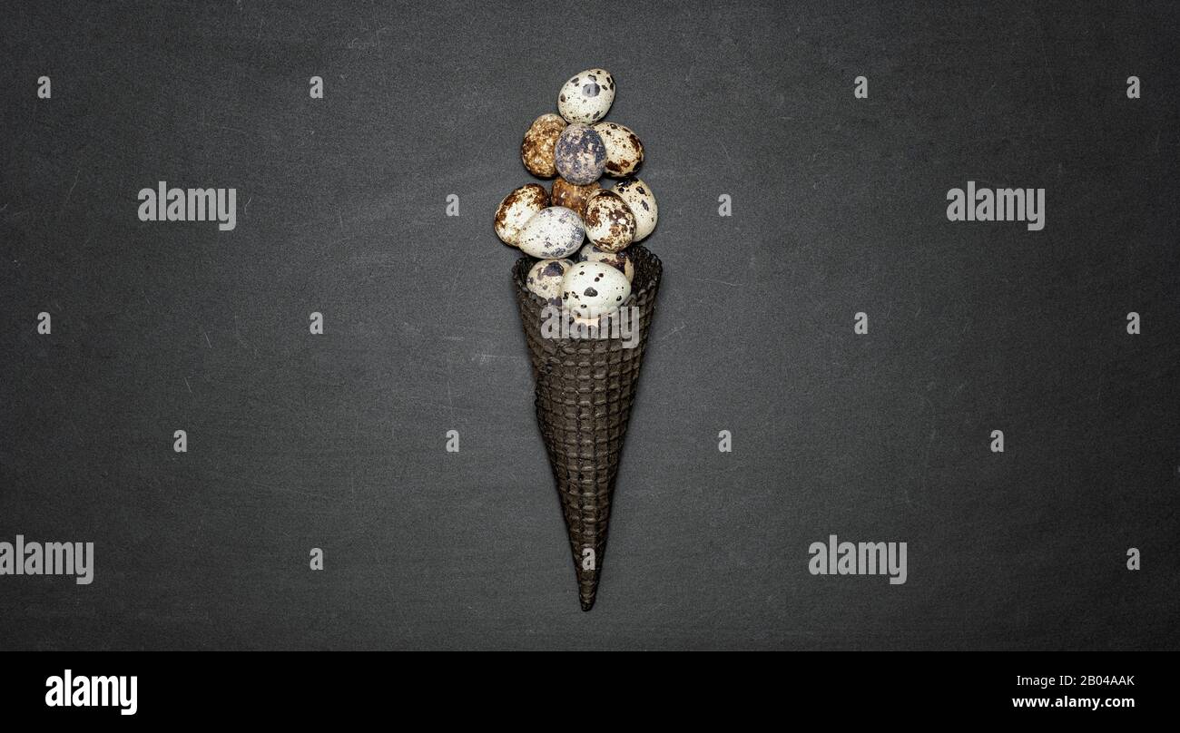 Dark waffle cone with easter eggs on a black background. Space for text. View from above. Flat lay. Stock Photo