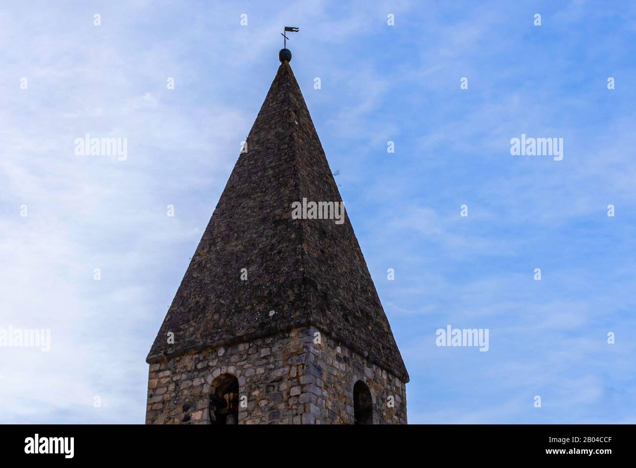 The tower of a European church in a small French village against the background of clear blue sky (Guillaumes, France) Stock Photo