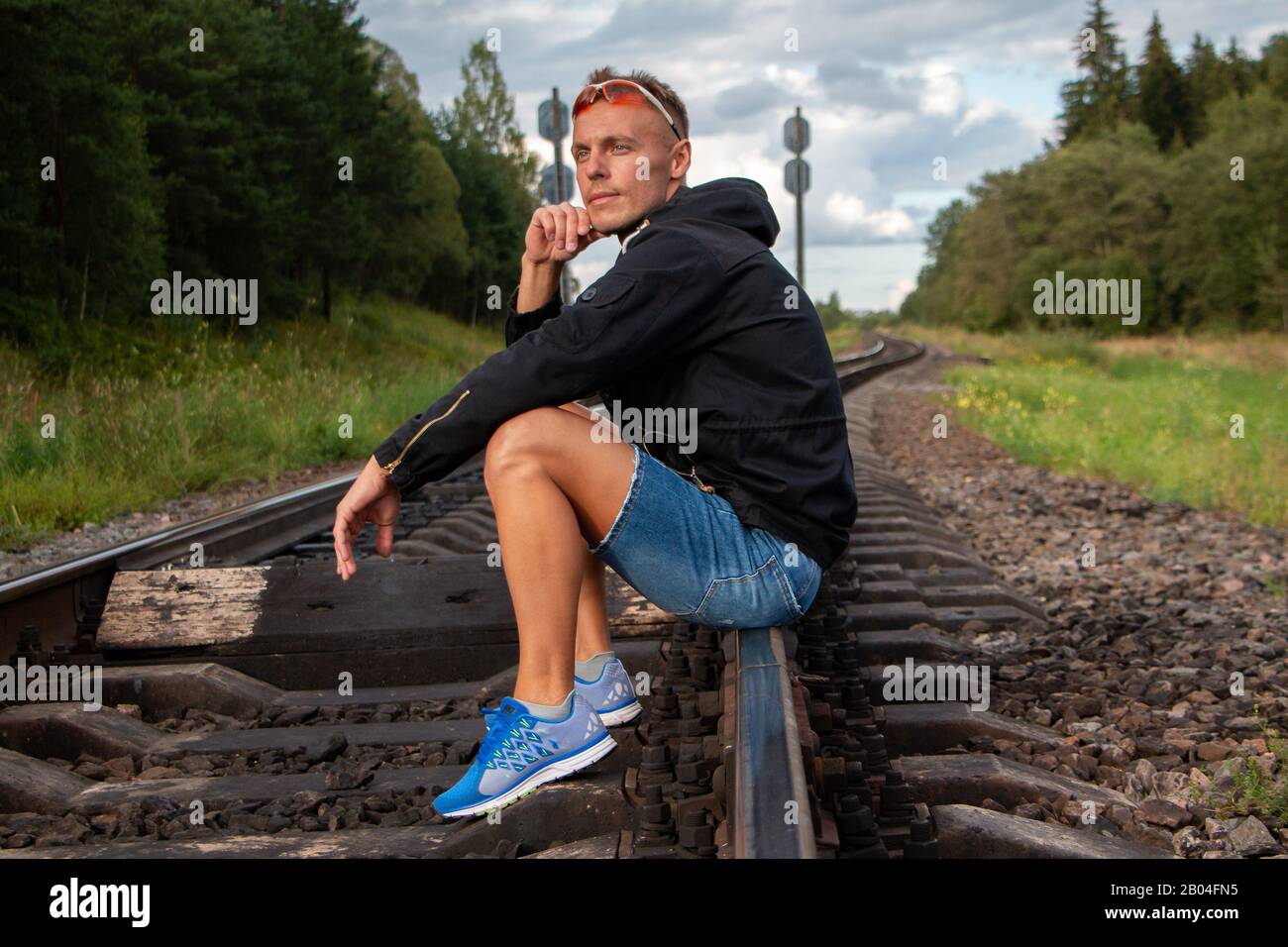 The man is sitting on the rails and thinking. Stock Photo