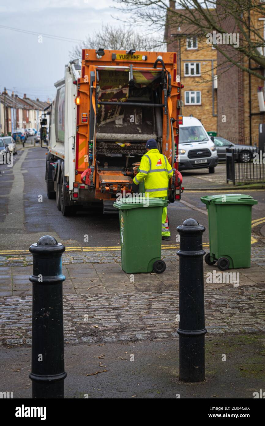 A bin man loading rubbish trash or garbage onto a rubbish truck or garbage truck Stock Photo