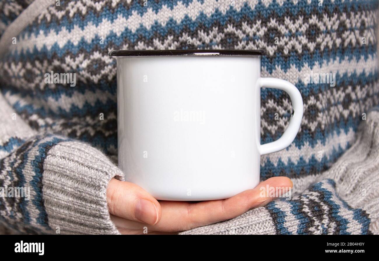 Enamel Mug with black edge line Mock-up. Girl holds white old-tin campfire cup in her hands Stock Photo