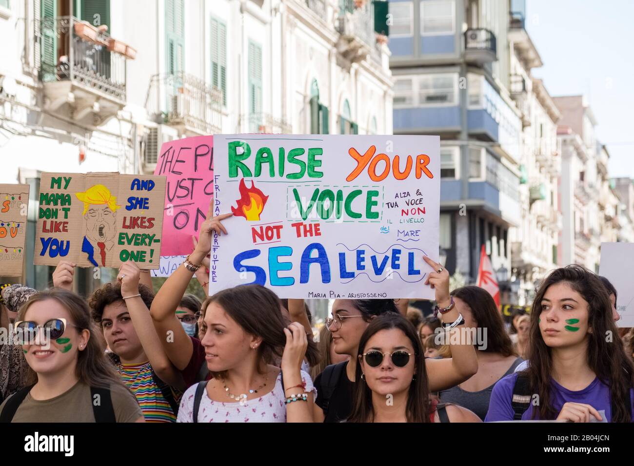 A procession made up of many young students protesting against climate change by displaying placards and banners with messages. Stock Photo