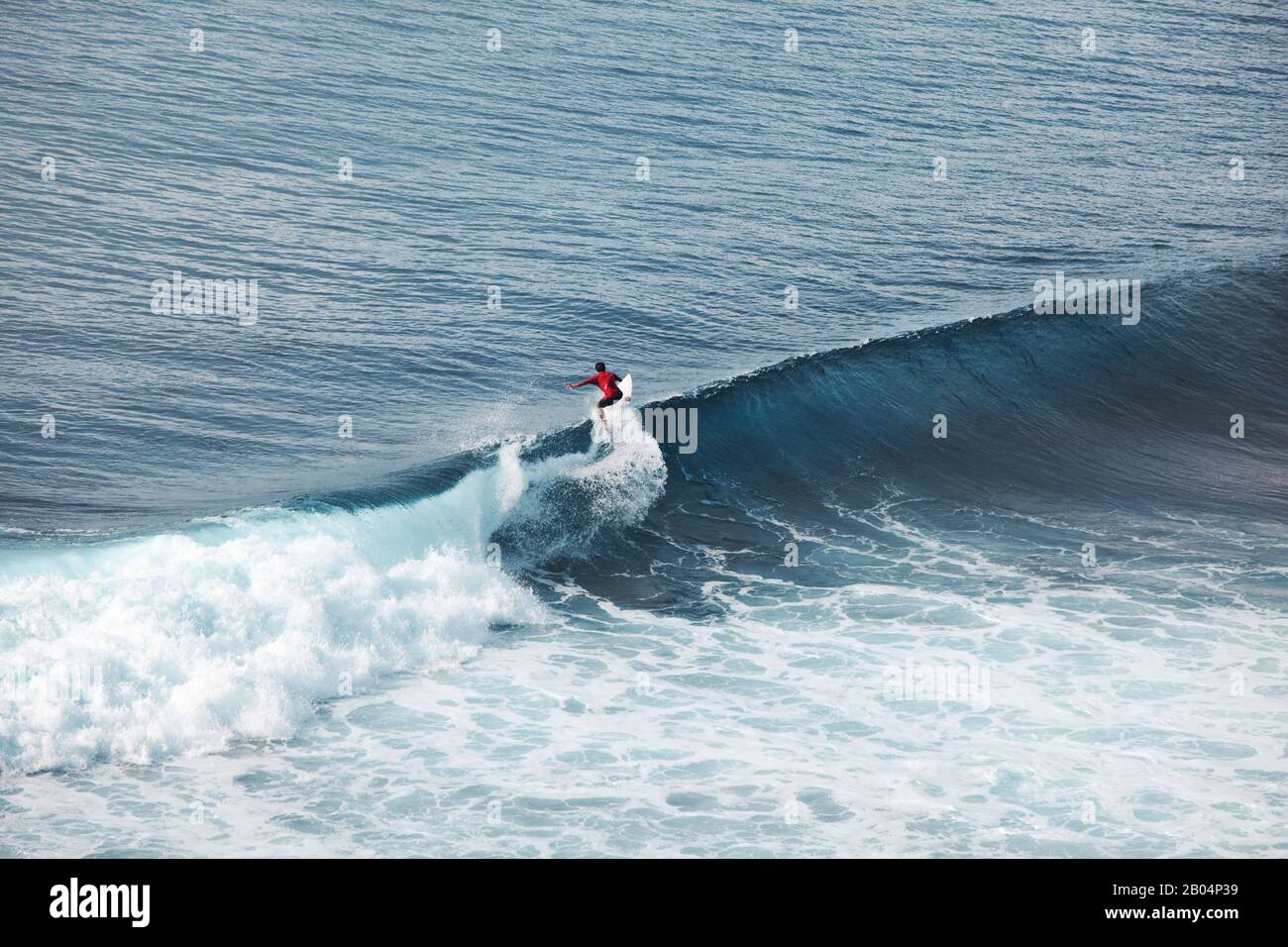Surfer in ocean on big waves. Bali surfing aerial shot. water sports. Healthy Active Lifestyle. Surfing. Summer Vacation. Extreme Sport. Stock Photo