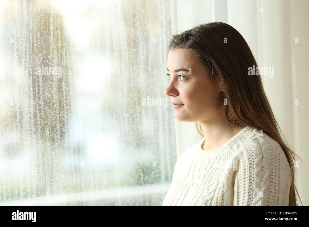 Side view portrait of a confident teen looking the rain through window Stock Photo