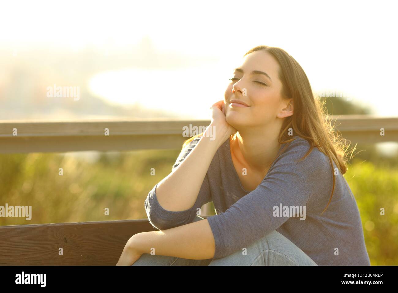 Satisfied woman relaxing sitting on a bench at sunset outdoors in city outskirts Stock Photo