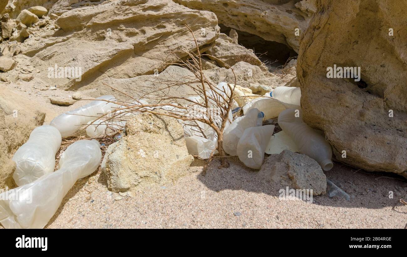 A dump of plastic trash near the rocks in the desert brought by the ...