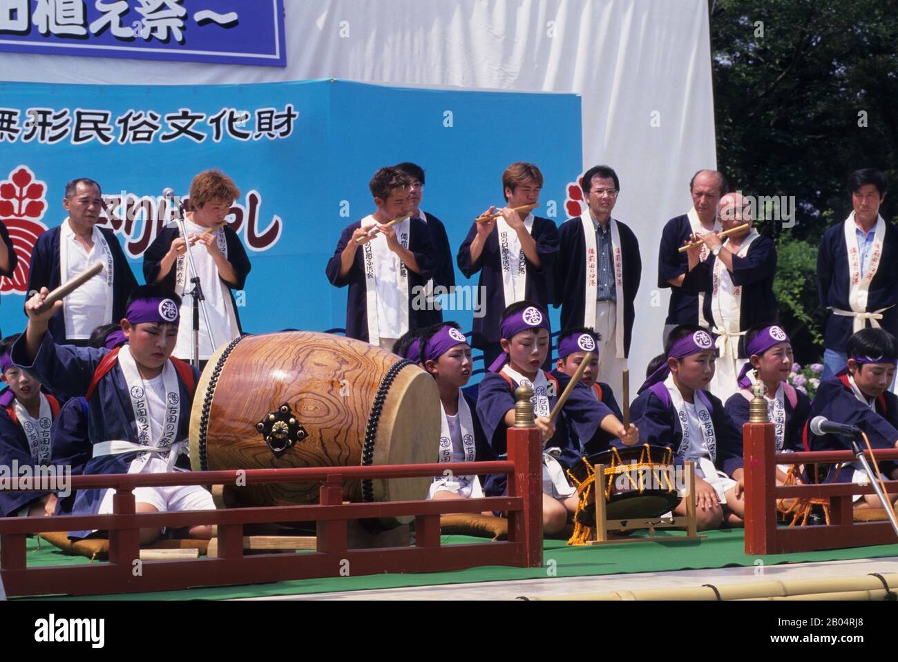 Japanese teenage boy playing a traditional Taiko drum in an orchestra during a farmer’s festival in the Korakuen Garden, a Japanese garden located in Stock Photo