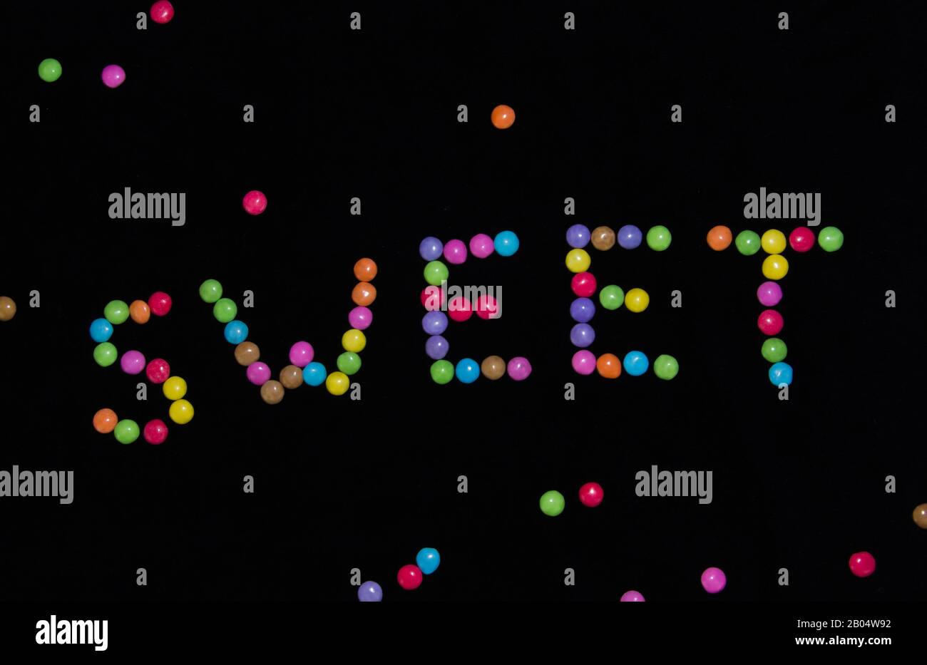 The word sweet flat laying on the table with colourful sweets on black ...